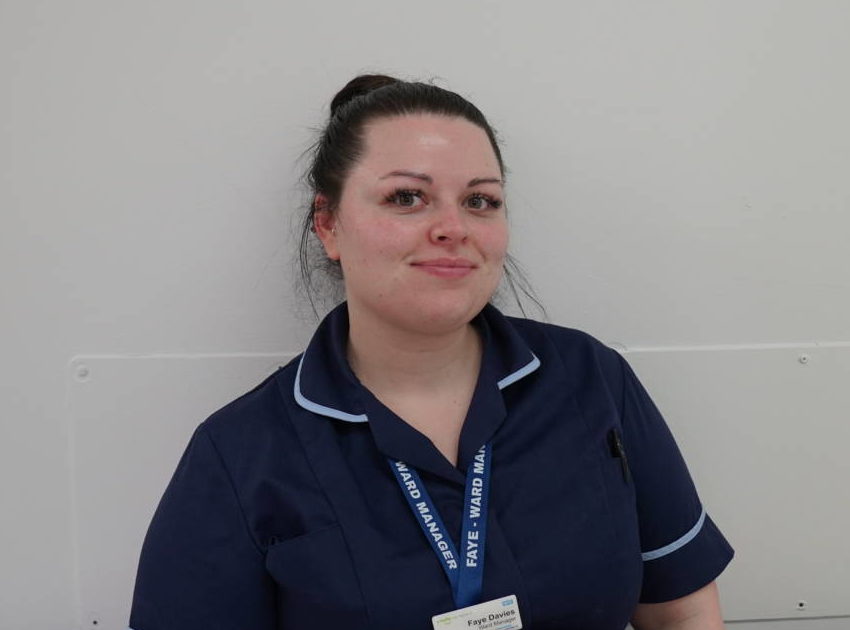 Photo of female with dark brown hair wearing a Ward Manager uniform which is Dark blue.